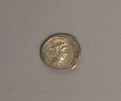 A worn silver Roman coin bearing the head of the young Octavian.